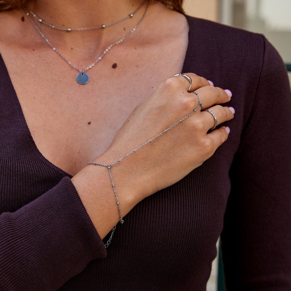 Sølvfarget håndkjede som binder sammen armbånd og ring